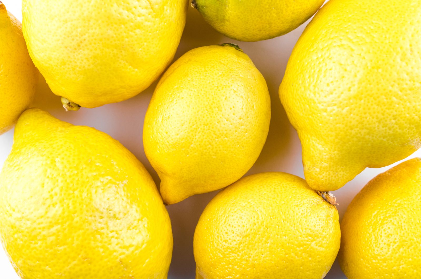 A bowl of fresh lemons with green leaves